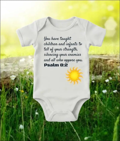 Soft baby bodysuit with Psalm 8:2 verse print, grass background.