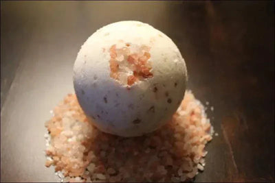 Organic detox bath bomb with pink bath salts on wooden background.